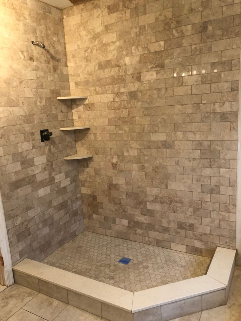 A bathroom with a walk in shower and a brick wall.