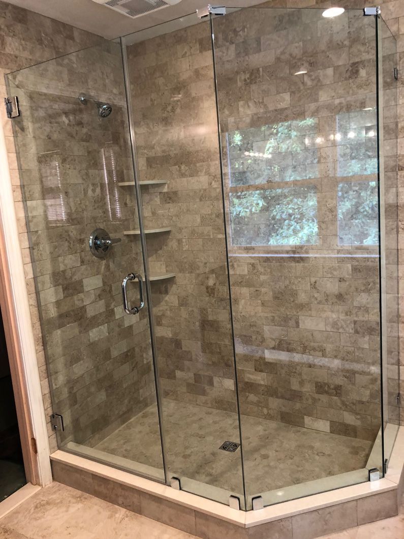 A bathroom with a walk in shower with a glass door.