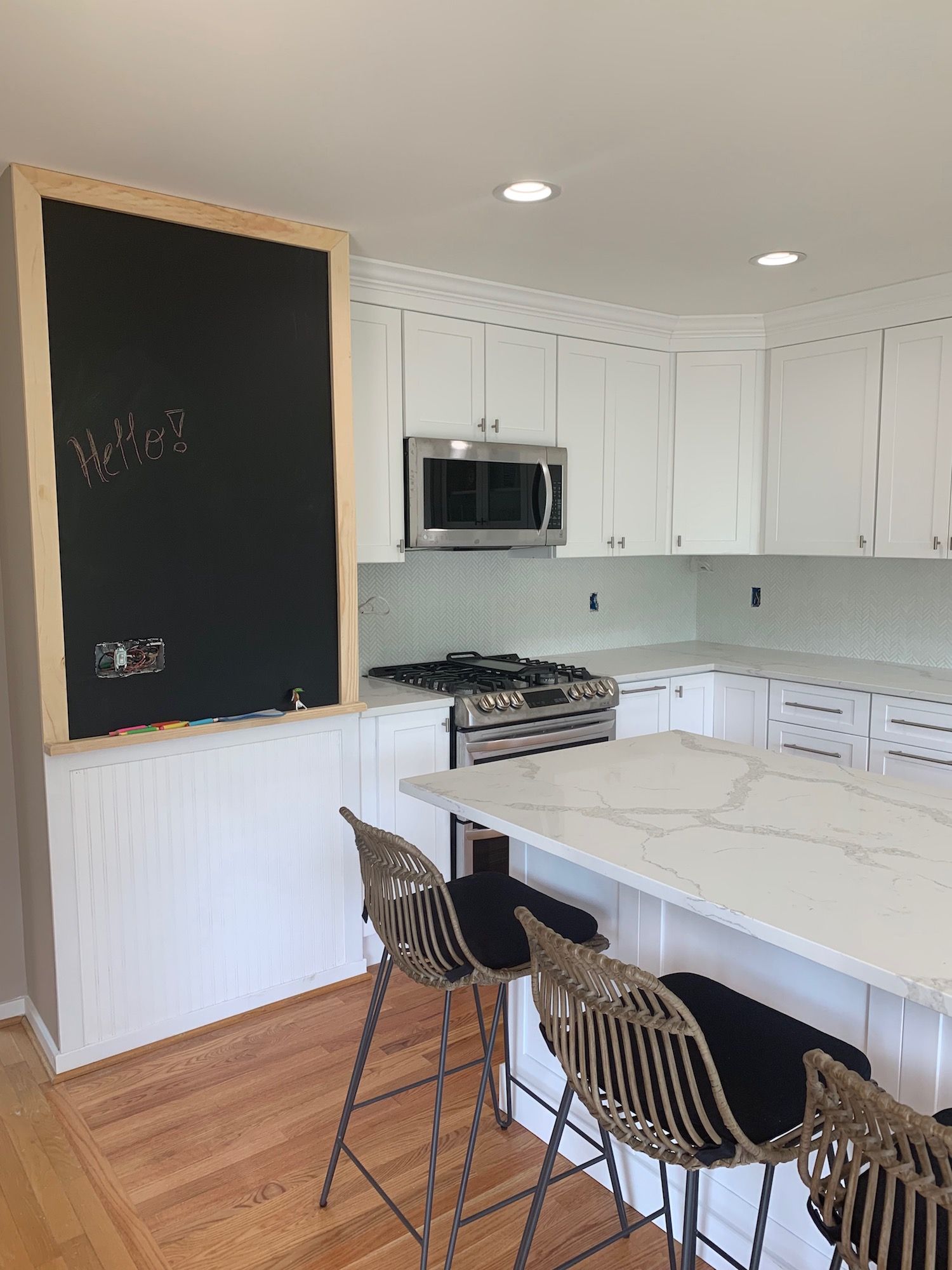 A kitchen with white cabinets and a chalkboard on the wall.