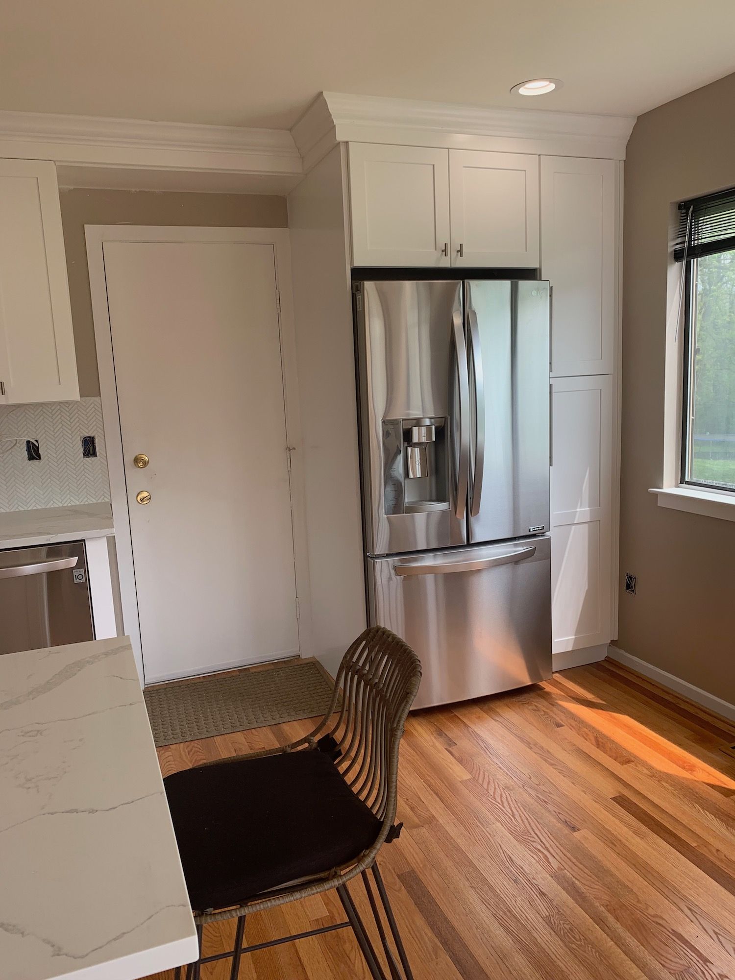A kitchen with a stainless steel refrigerator and a chair.