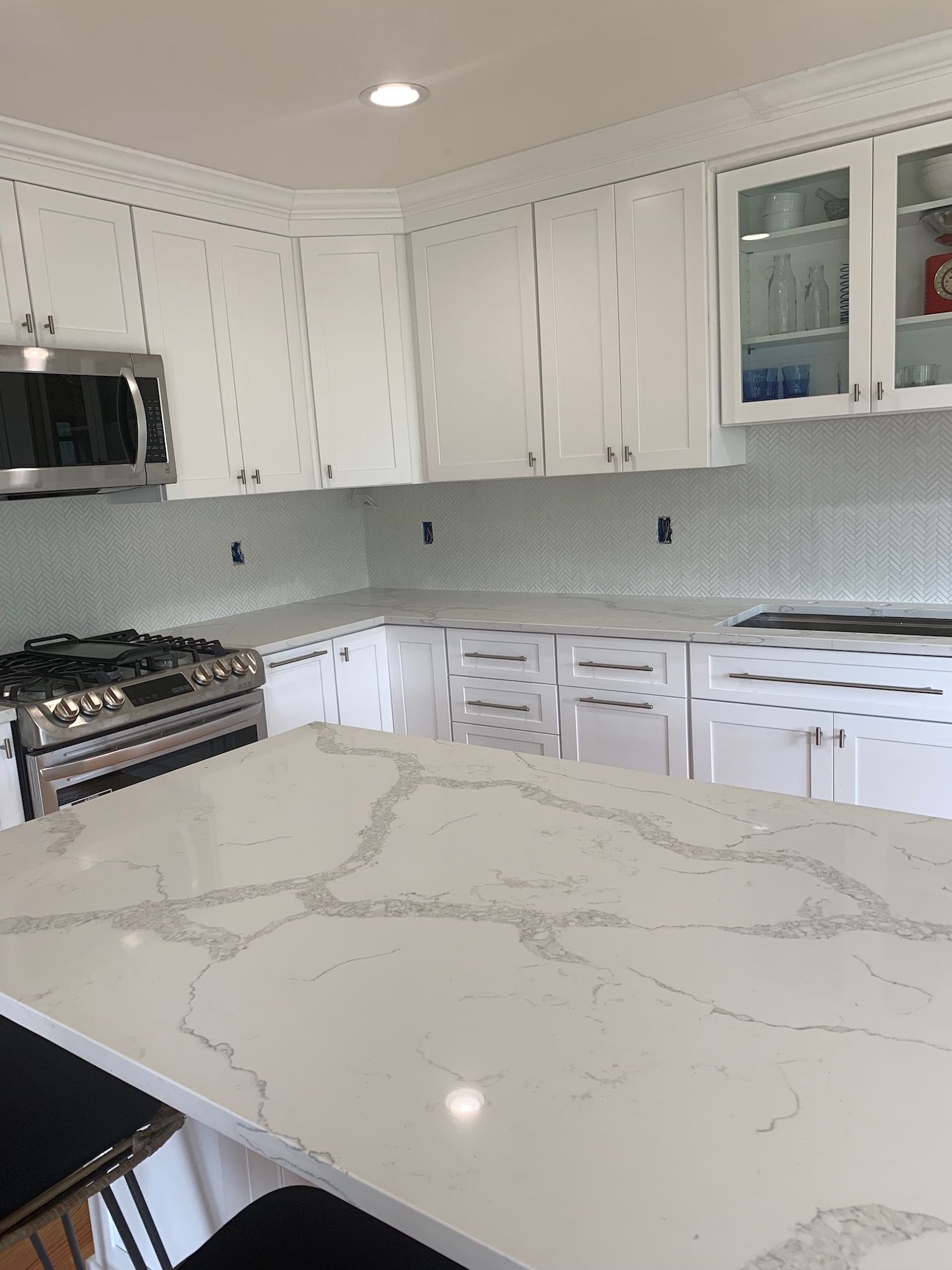 A kitchen with white cabinets , a stove and a microwave