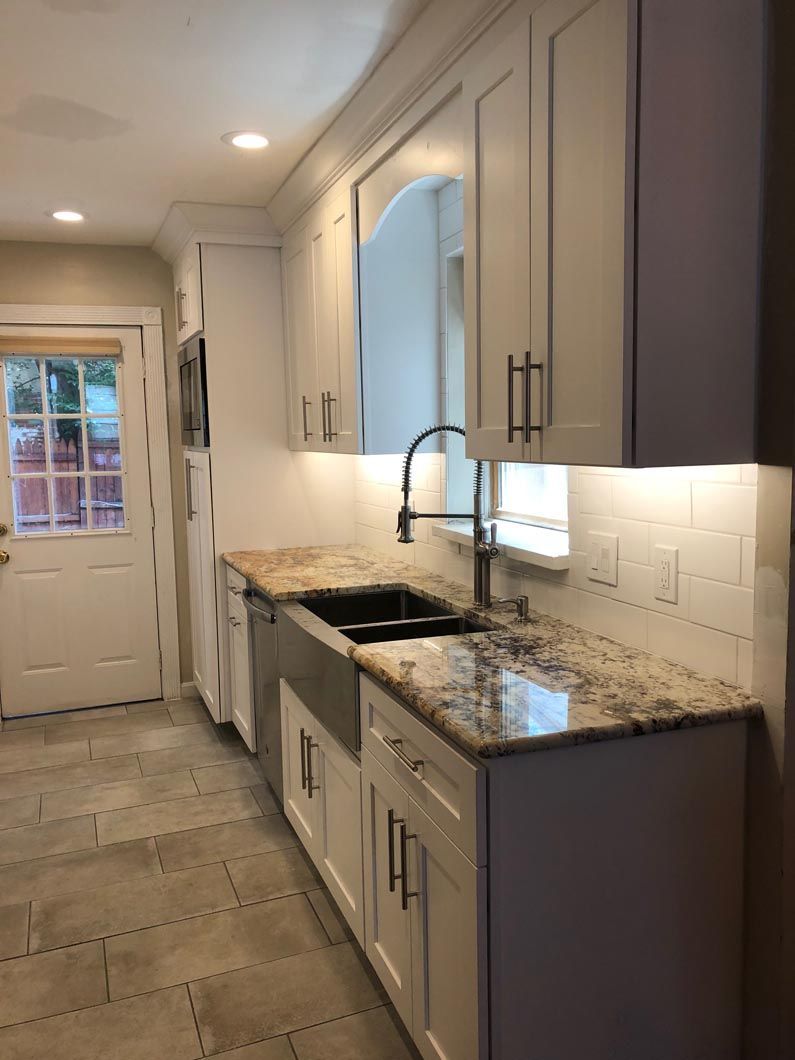 A kitchen with white cabinets , granite counter tops , and a sink.