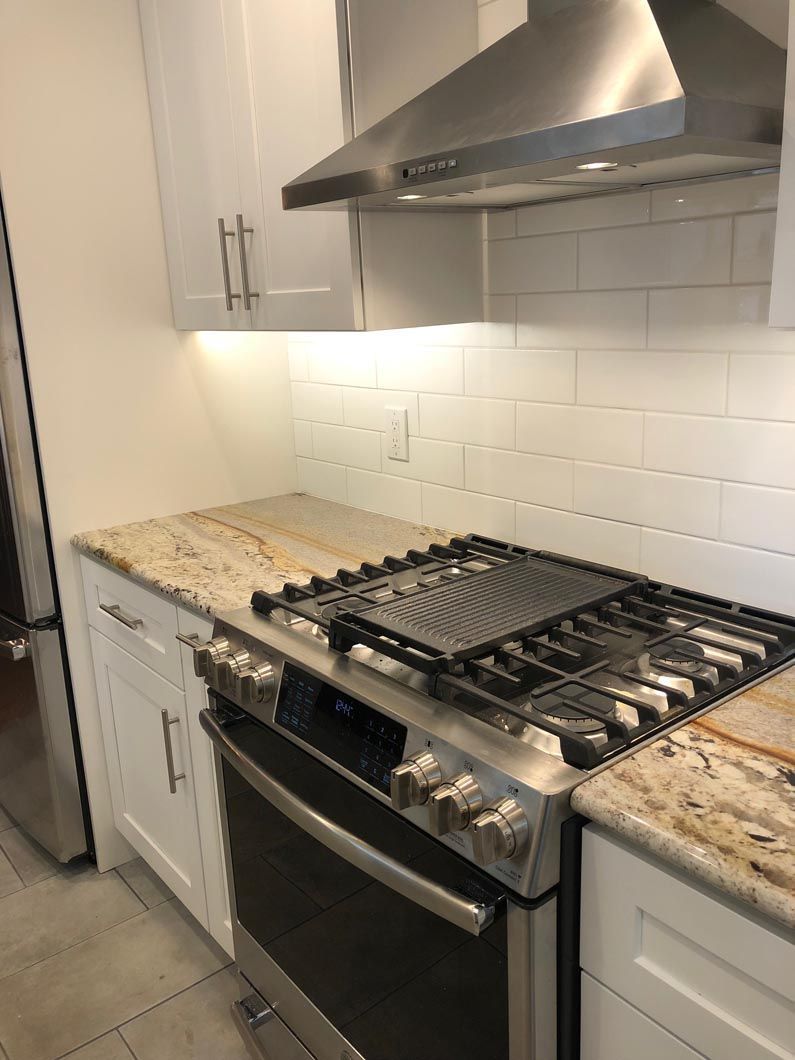 A kitchen with a stove top oven and a hood.