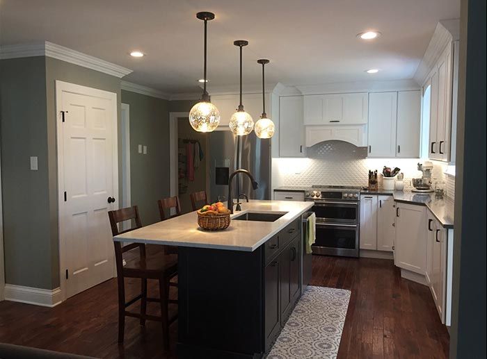 A kitchen with white cabinets and a large island in the middle.