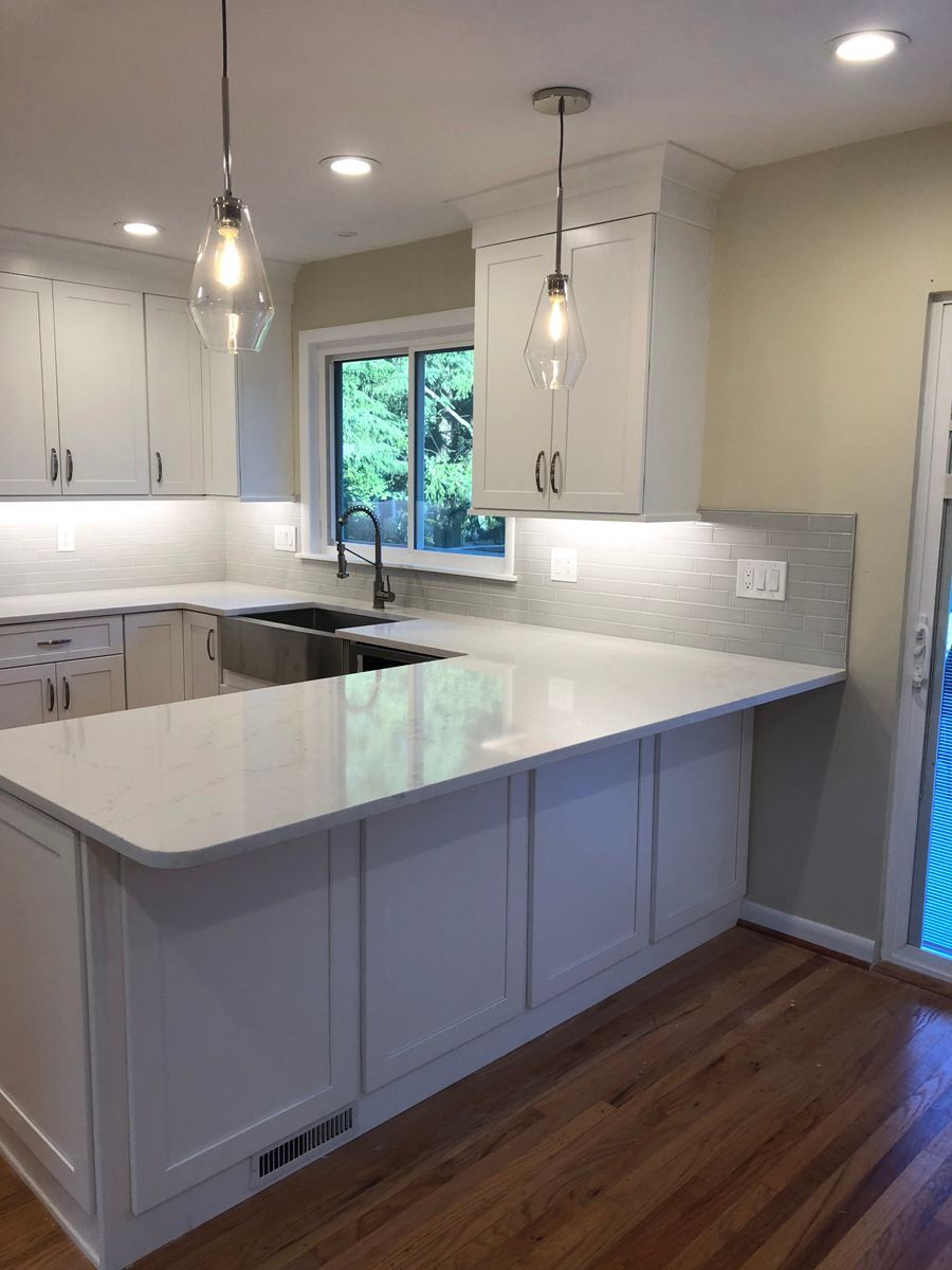 A kitchen with white cabinets , a sink , and a large island.