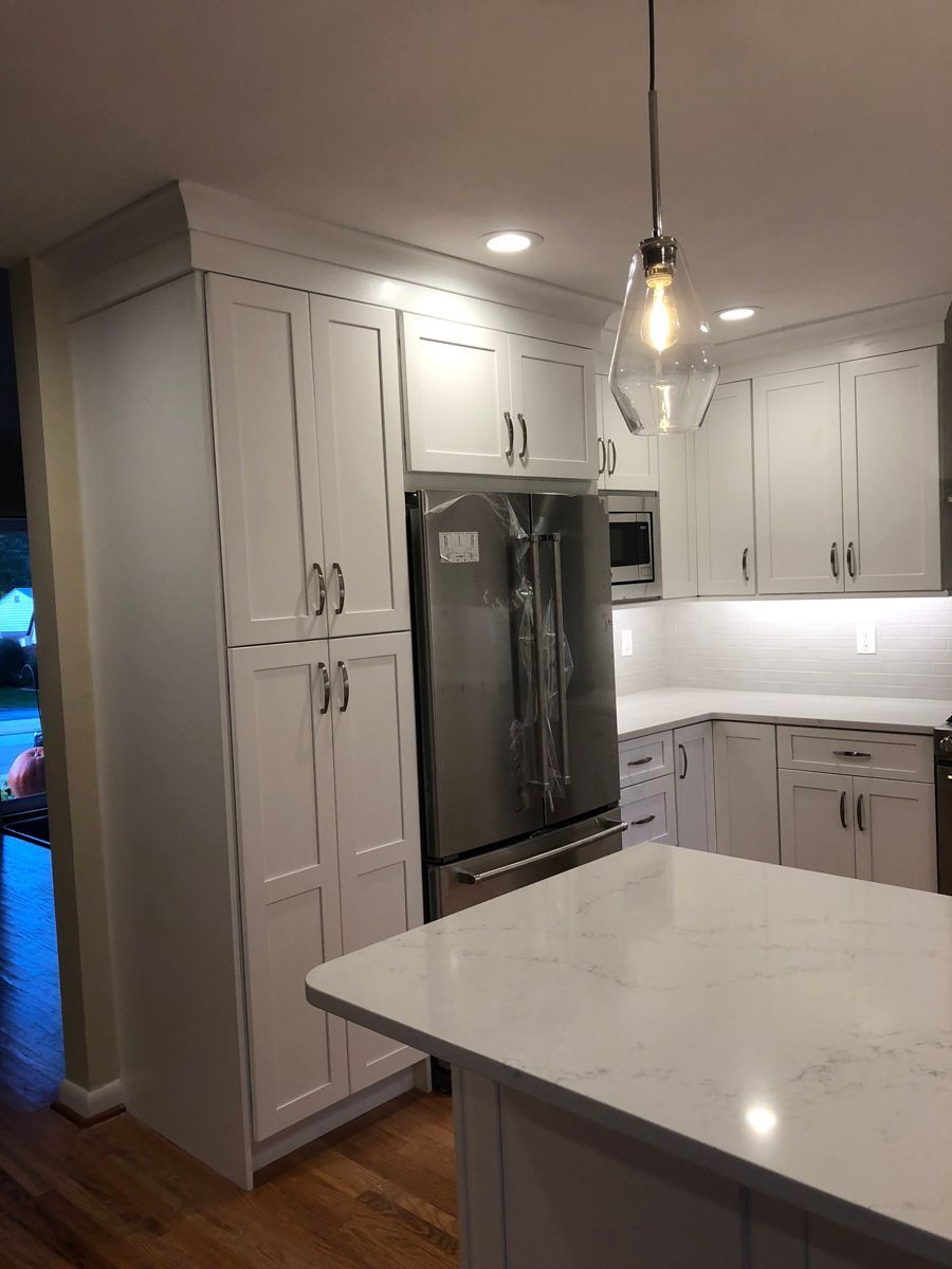 A kitchen with white cabinets , stainless steel appliances , and a large island.