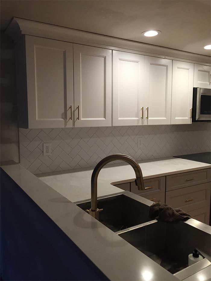A kitchen with white cabinets and a stainless steel sink