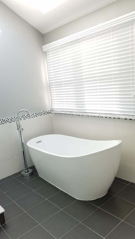 There is a bathtub in the bathroom next to a window.