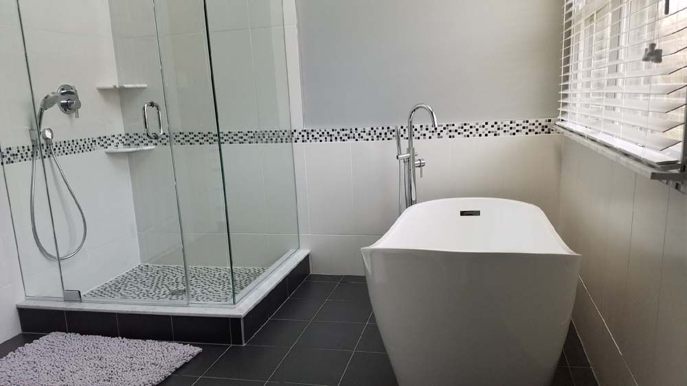 A bathroom with a tub , shower , and window.