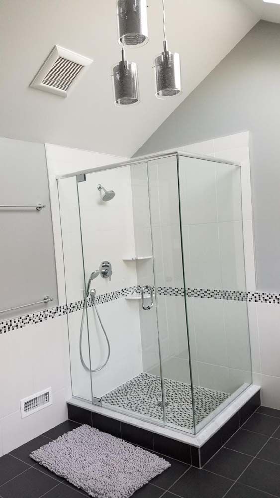 A bathroom with a walk in shower and a rug on the floor.