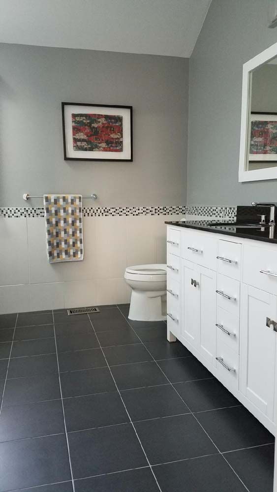 A bathroom with a toilet , sink and mirror.