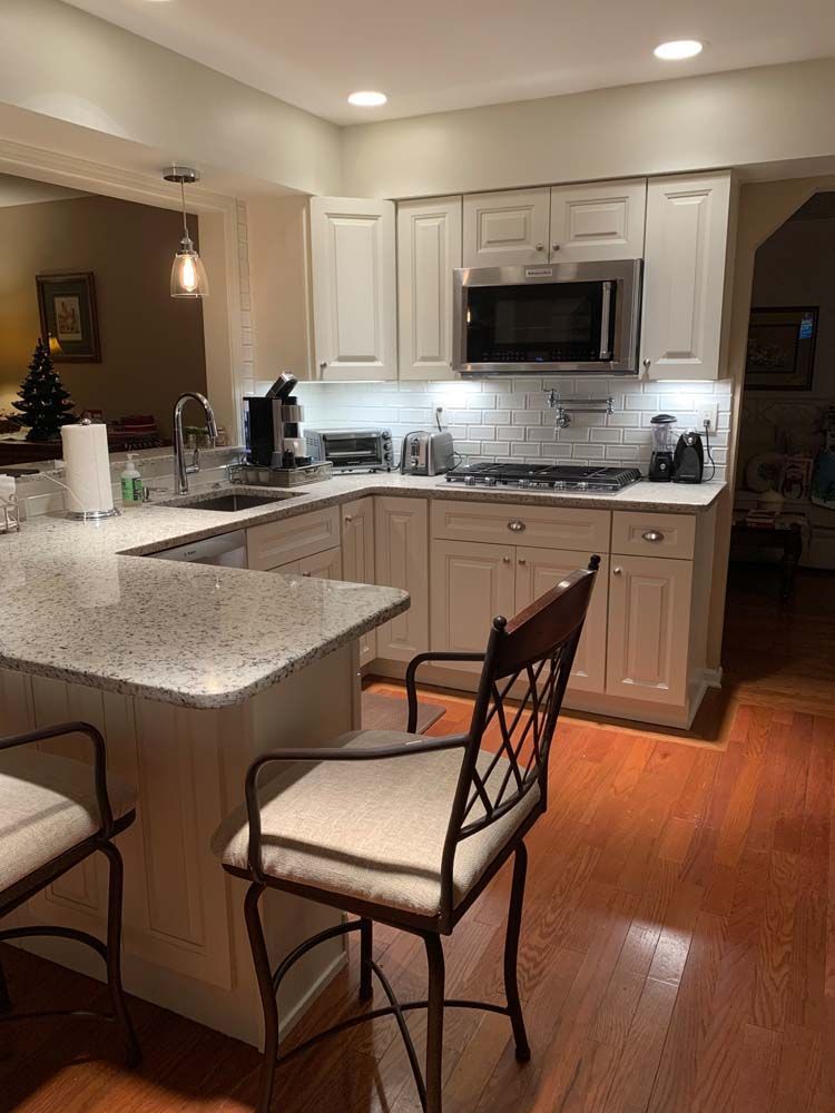 A kitchen with white cabinets , granite counter tops , stainless steel appliances , a microwave and a sink.