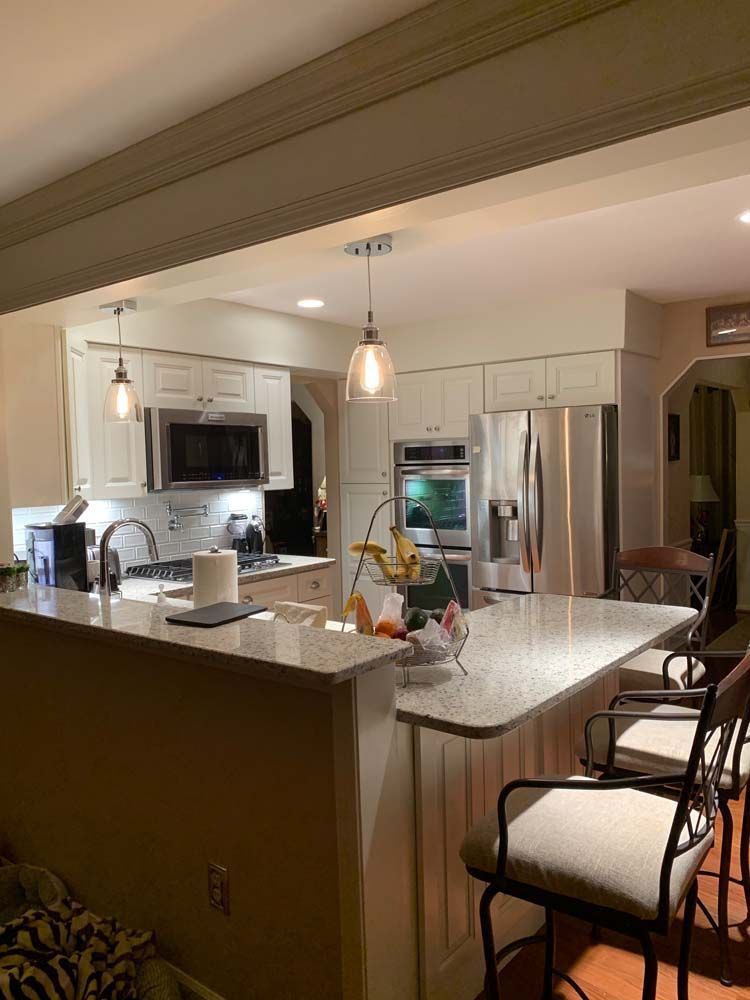 A kitchen with white cabinets , stainless steel appliances , a marble counter top , and a large island.