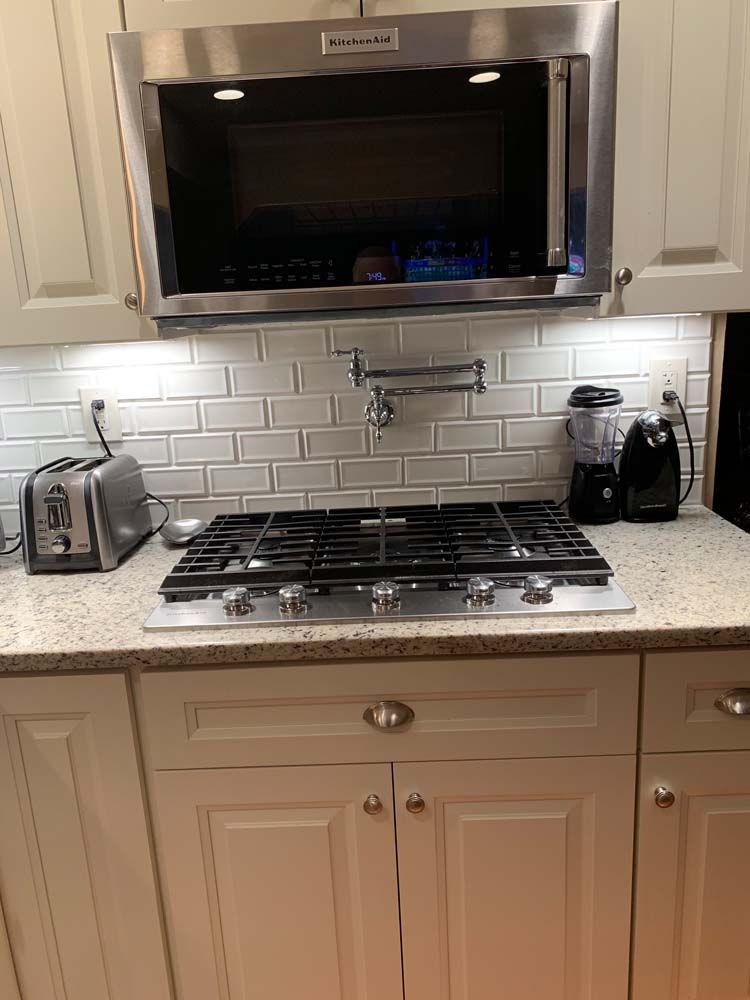 A kitchen with a stove , microwave , toaster and blender.