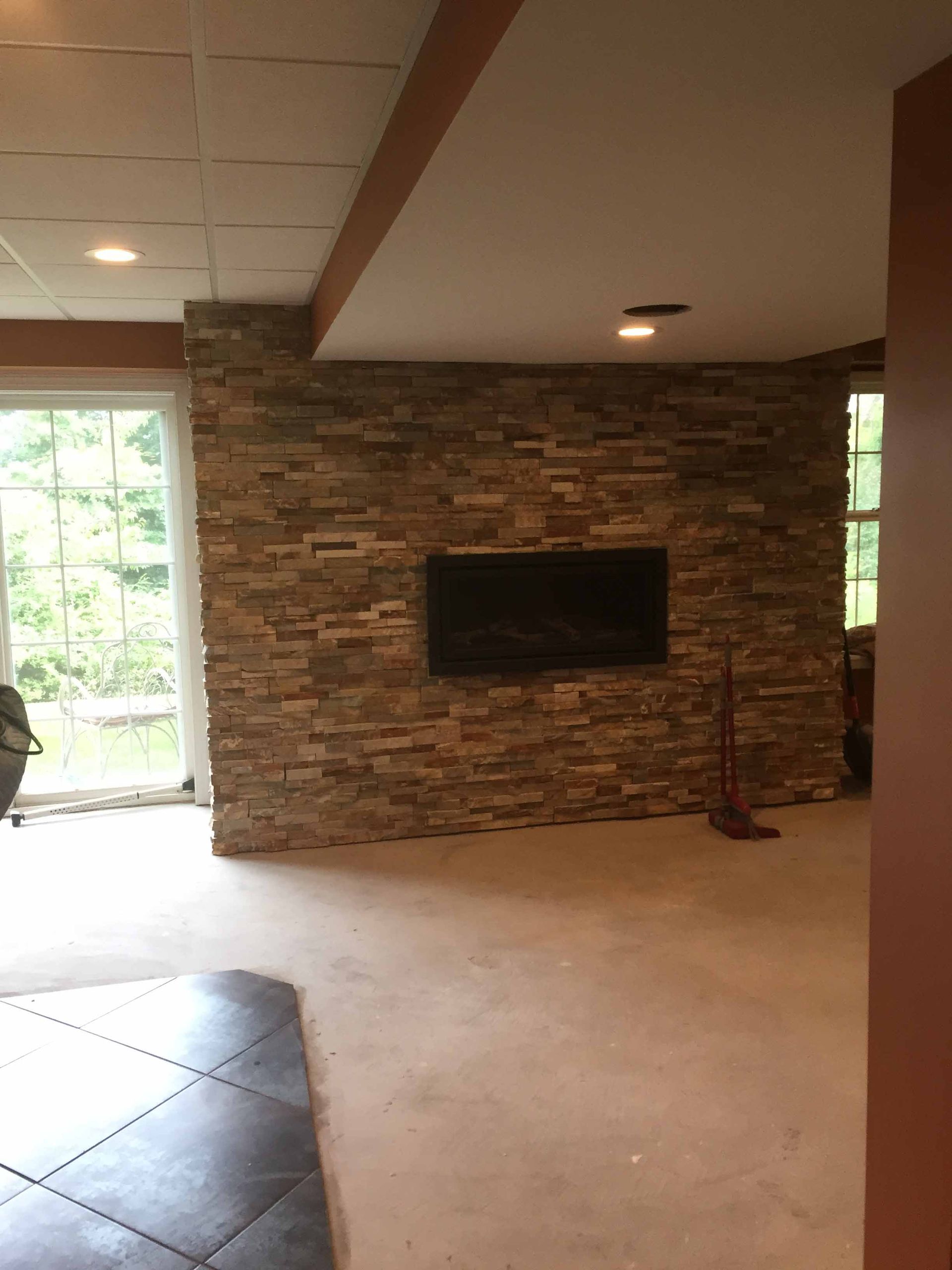 A living room with a stone wall and a flat screen tv on the wall.