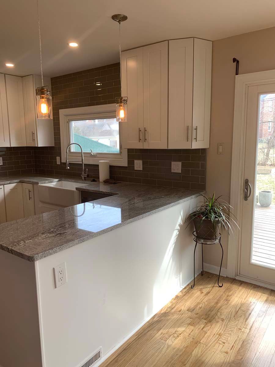 A kitchen with white cabinets , granite counter tops , a sink , and a window.