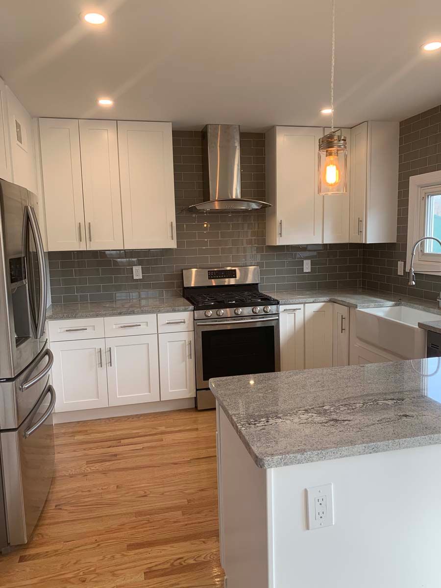 A kitchen with white cabinets , stainless steel appliances , granite counter tops , and hardwood floors.