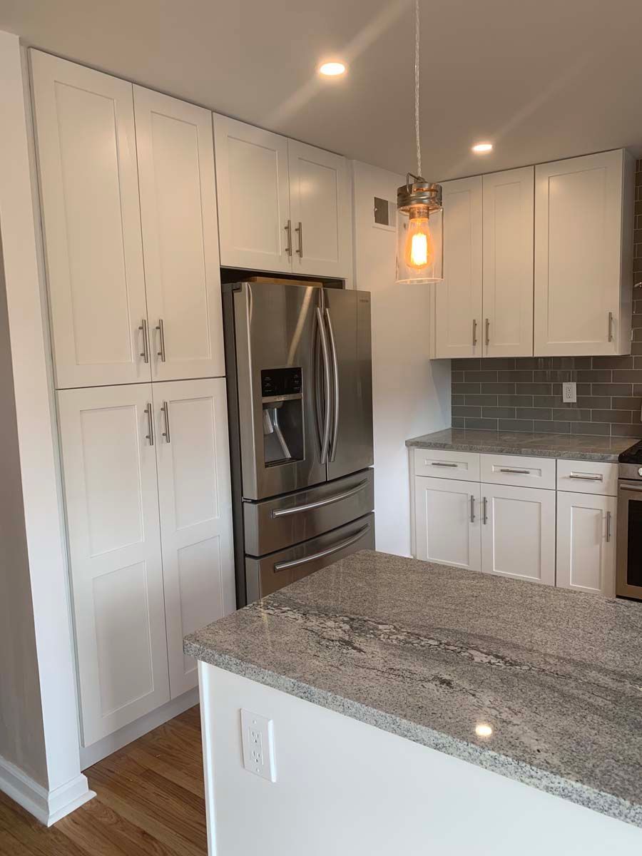 A kitchen with stainless steel appliances , granite counter tops , and white cabinets.