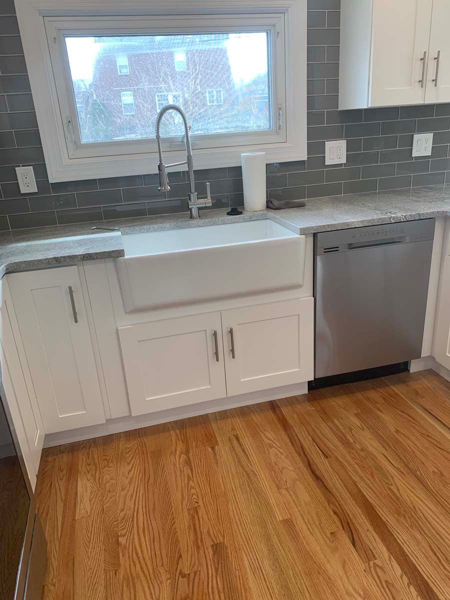 A kitchen with a sink , cabinets , a dishwasher and a window.
