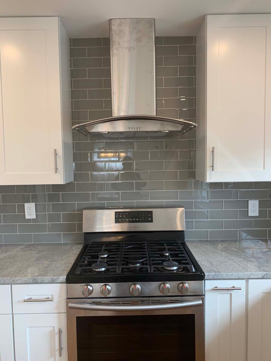 A kitchen with a stove top oven and a hood above it.