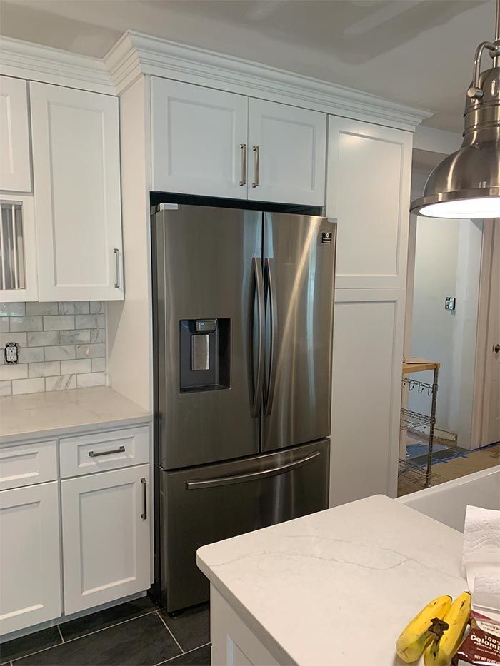 A kitchen with white cabinets and a stainless steel refrigerator