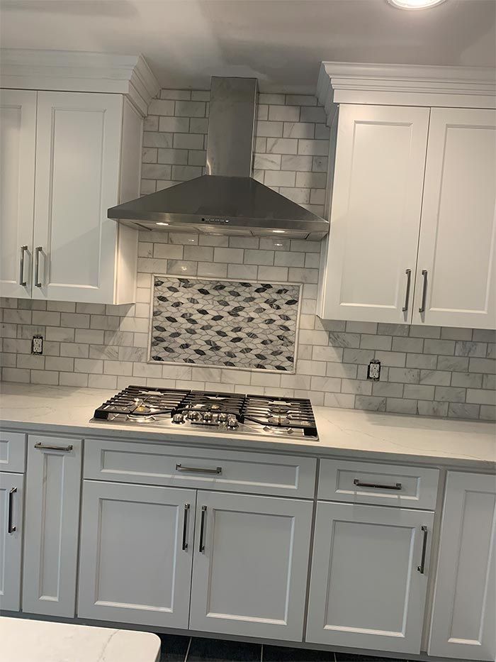 A kitchen with white cabinets and a stove top oven.