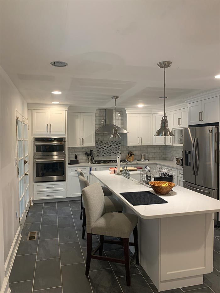A kitchen with white cabinets , stainless steel appliances , and a large island.
