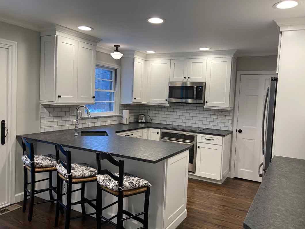 A kitchen with white cabinets , granite counter tops , stainless steel appliances and a large island.