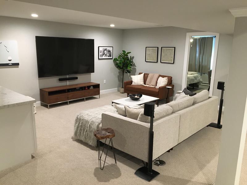 A living room with a couch , television , and speakers.