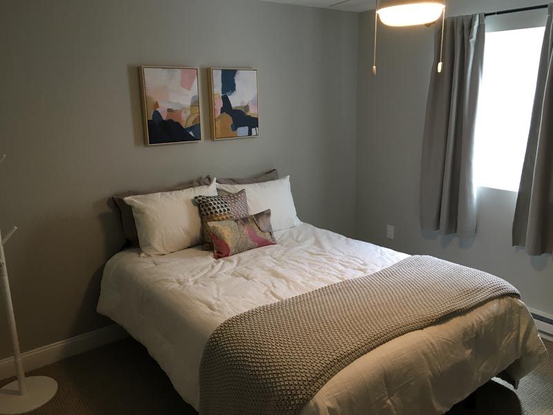 A bedroom with a bed and two paintings on the wall