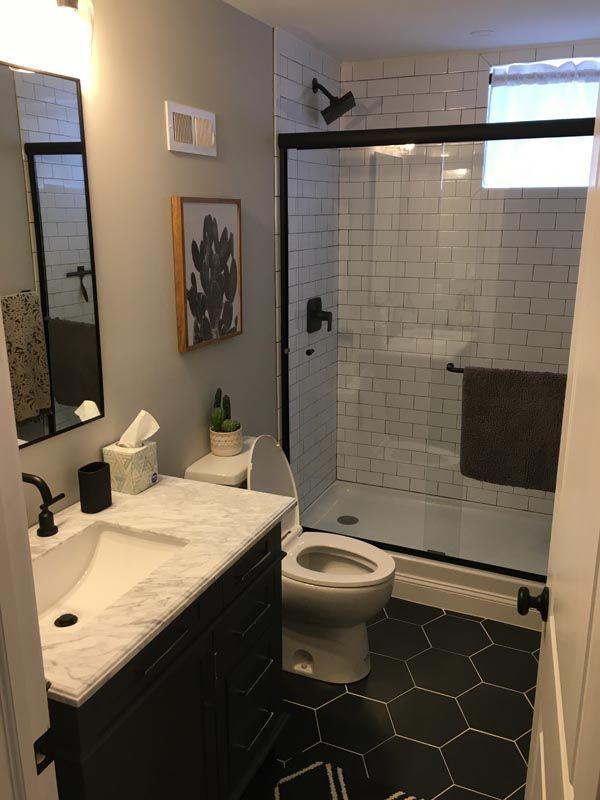 A bathroom with a toilet , sink , mirror and shower.