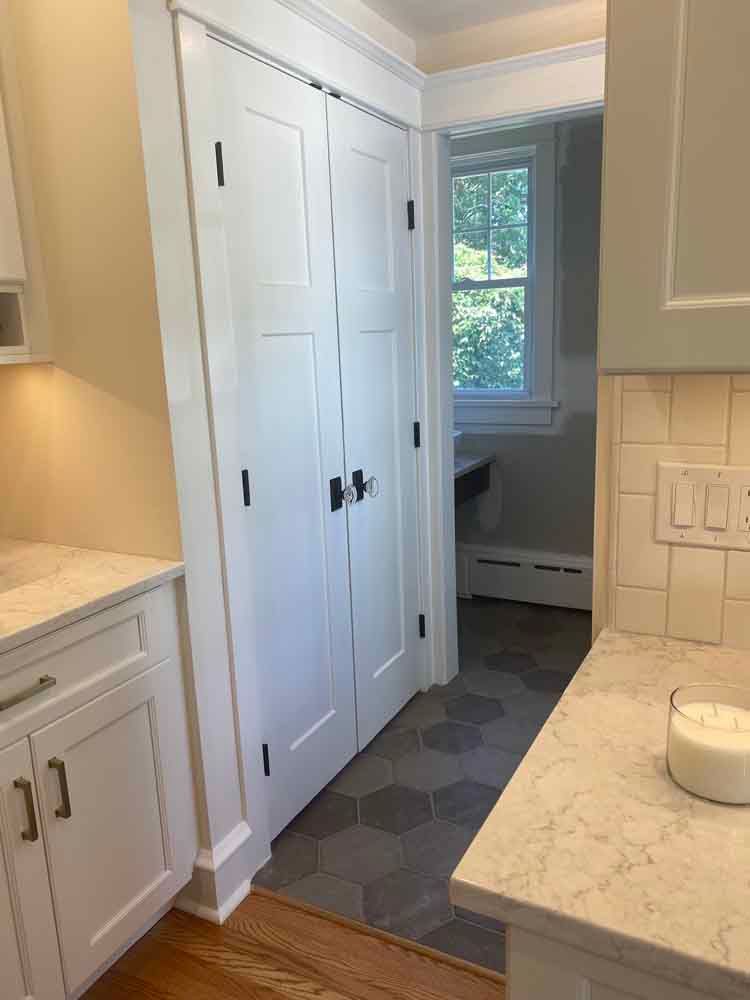 A kitchen with white cabinets and a marble counter top.