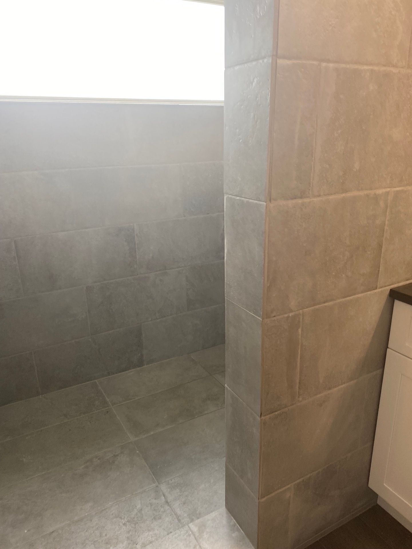 A bathroom with a walk in shower and a window.