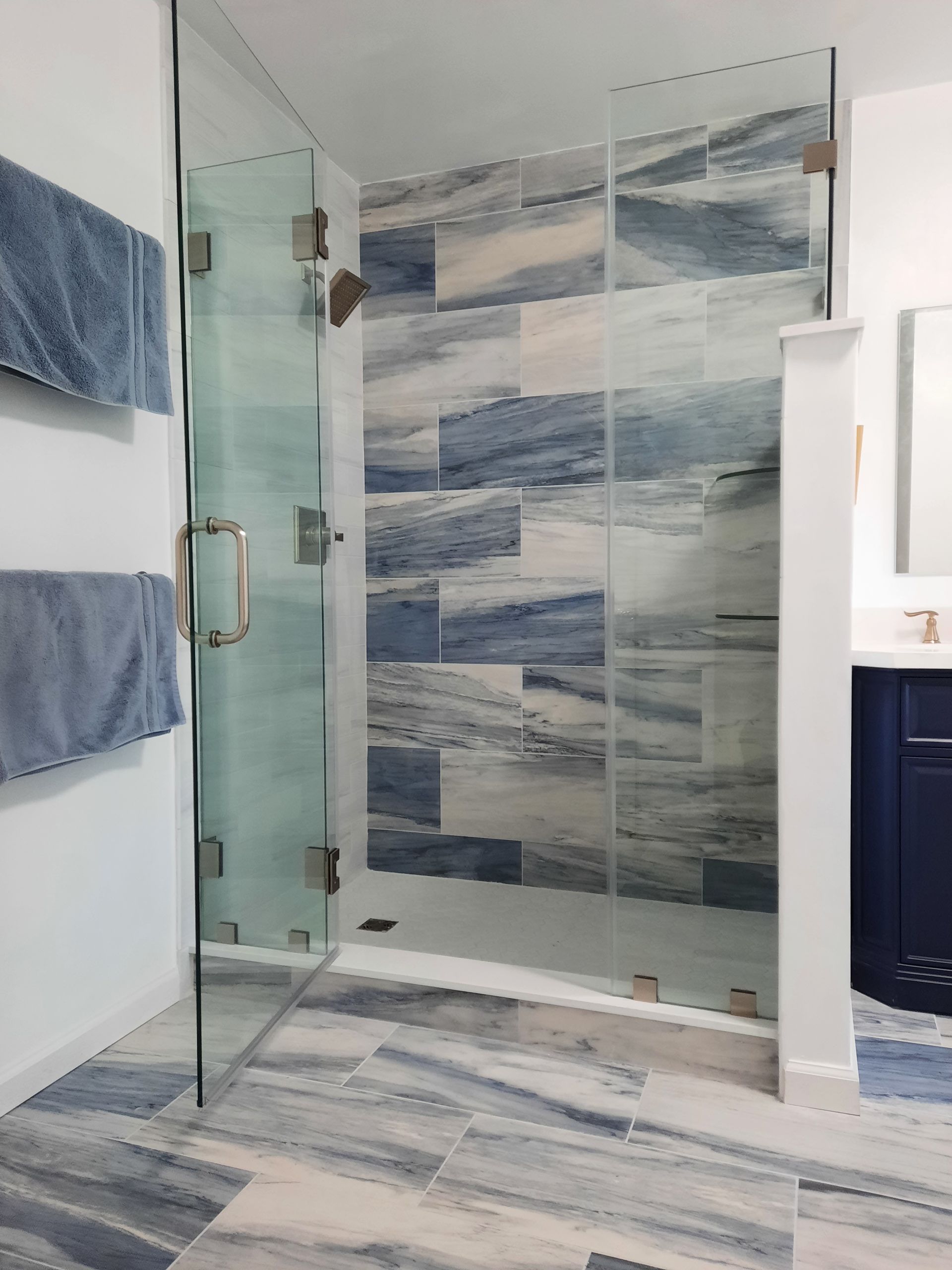 A bathroom with a walk in shower and a glass door.