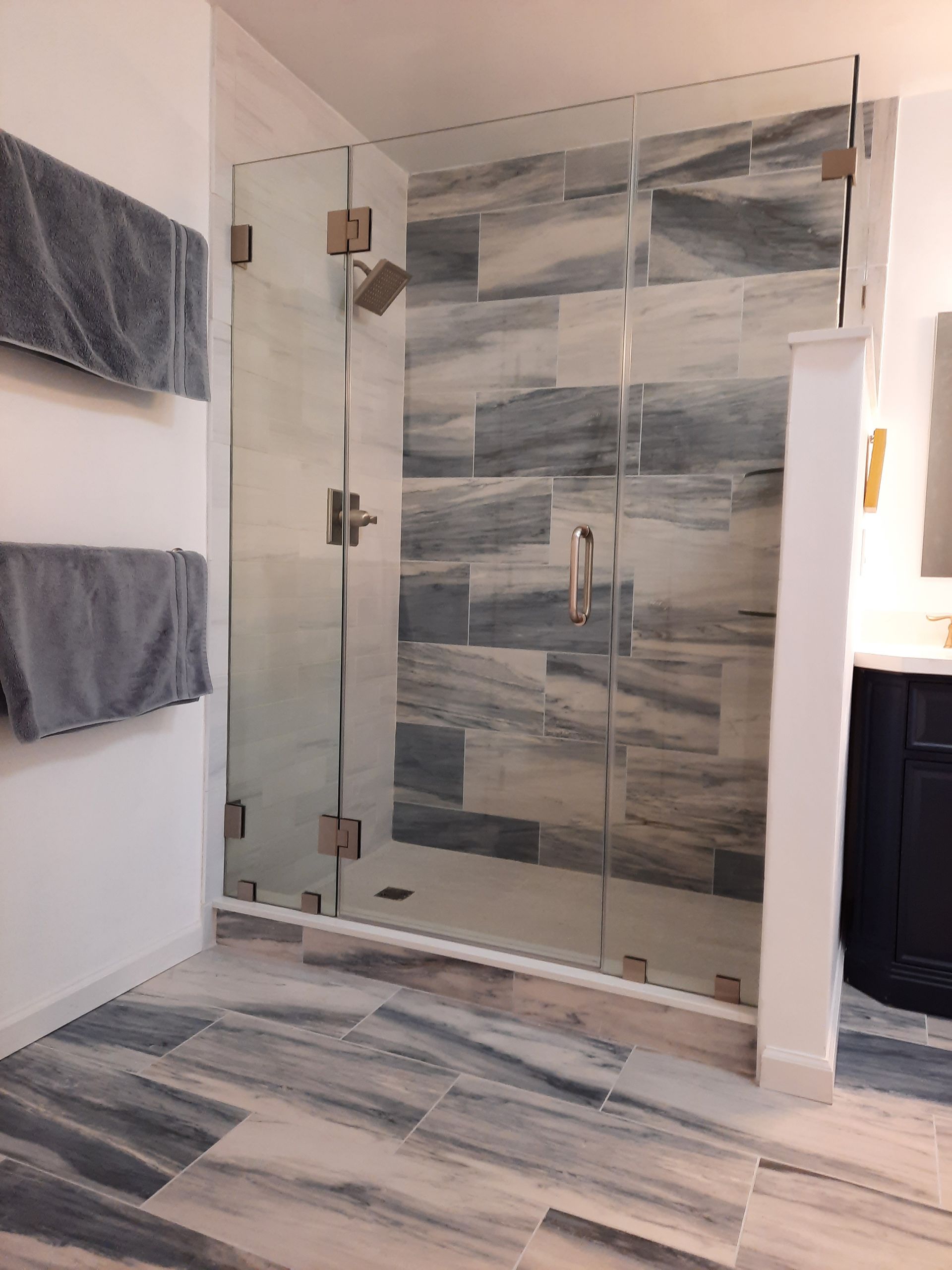 A bathroom with a walk in shower with a glass door