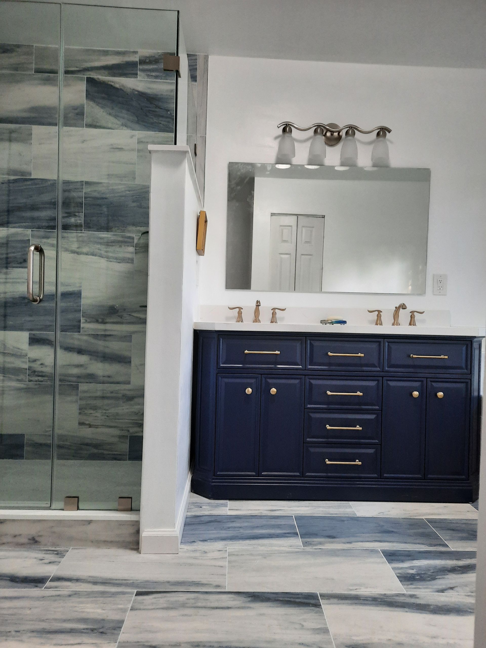 A bathroom with blue cabinets and a large mirror
