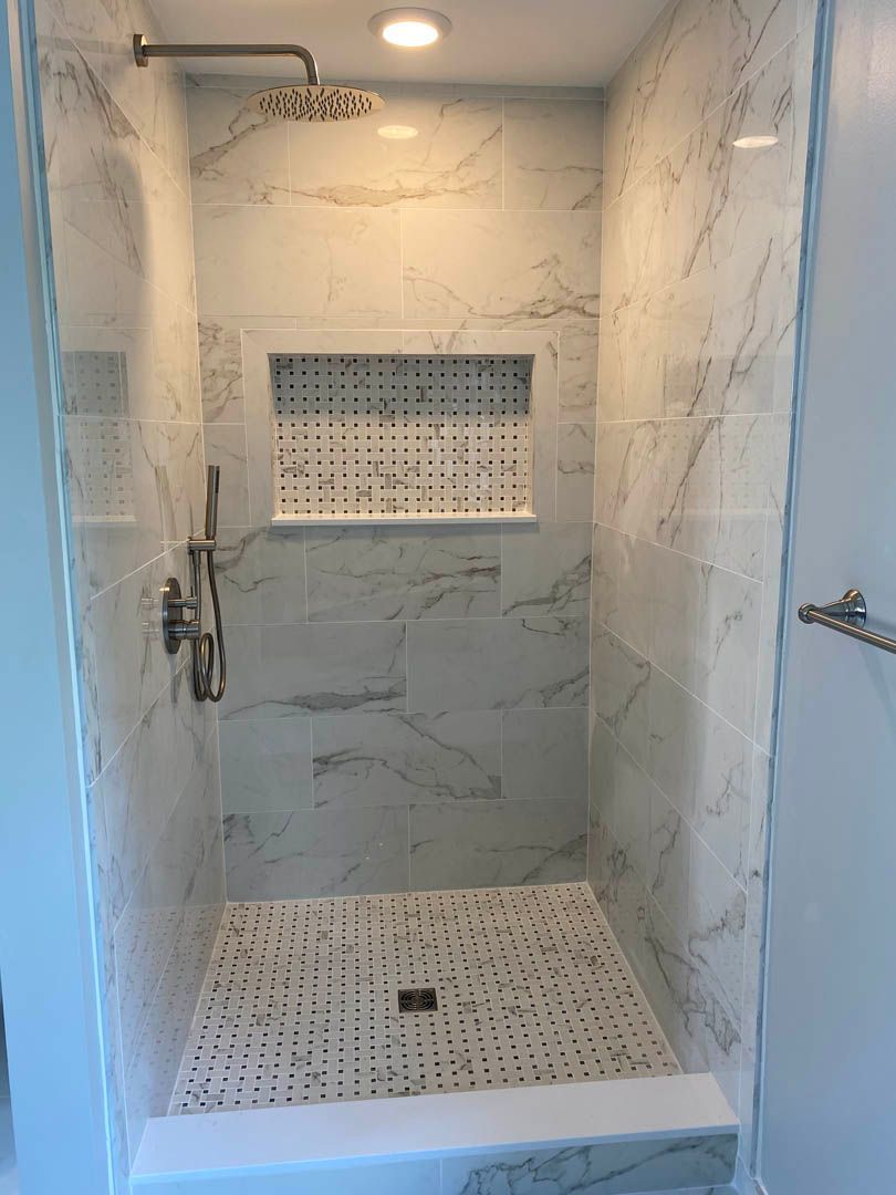 A shower with marble tiles and a shower head.