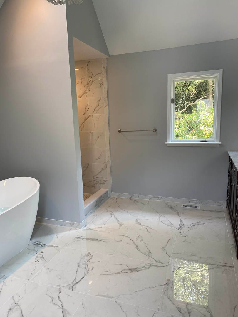 A bathroom with a tub , shower and window.
