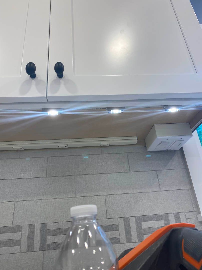 A bottle of water sits on a tiled floor in front of a cabinet