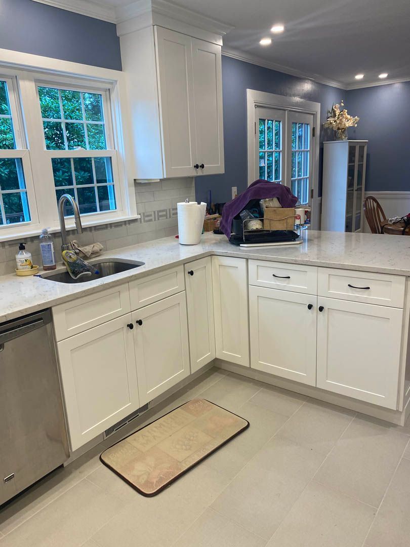 A kitchen with white cabinets , a sink , and a rug on the floor.