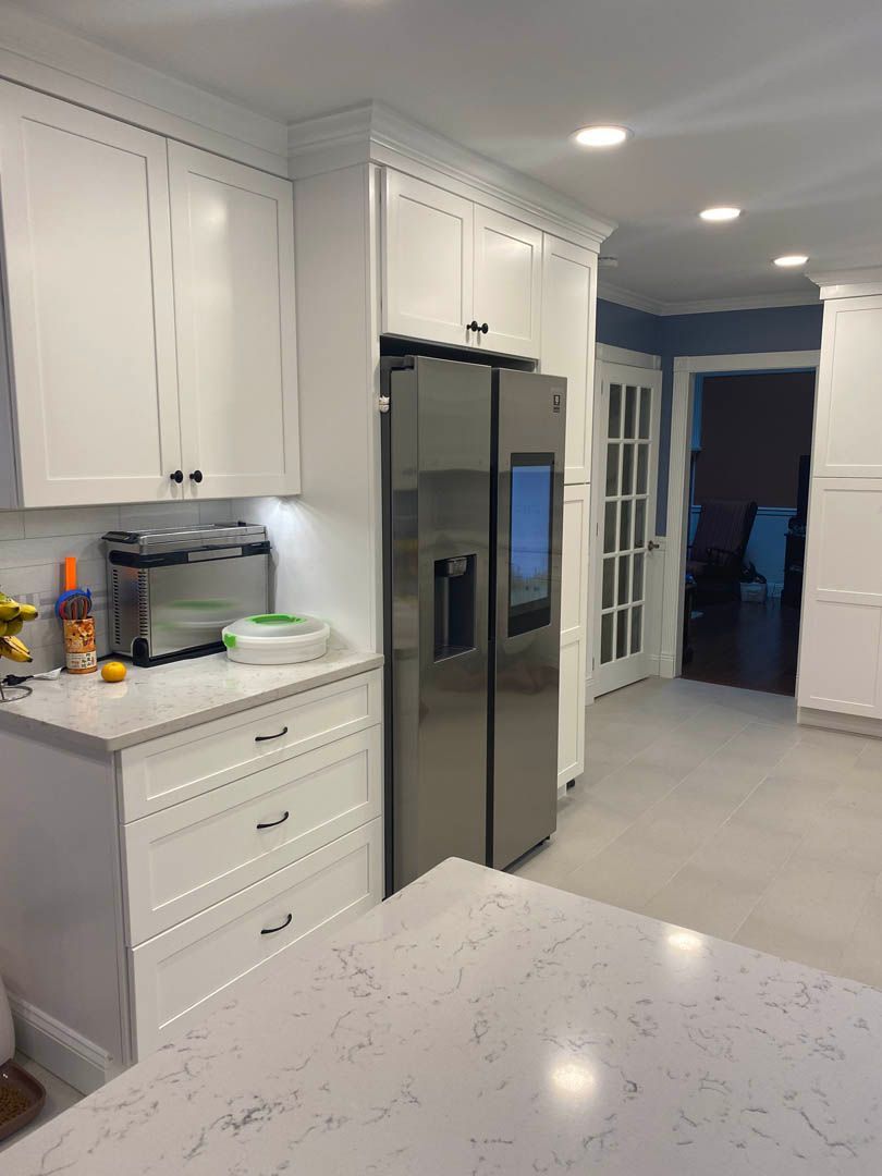 A kitchen with white cabinets and a stainless steel refrigerator.