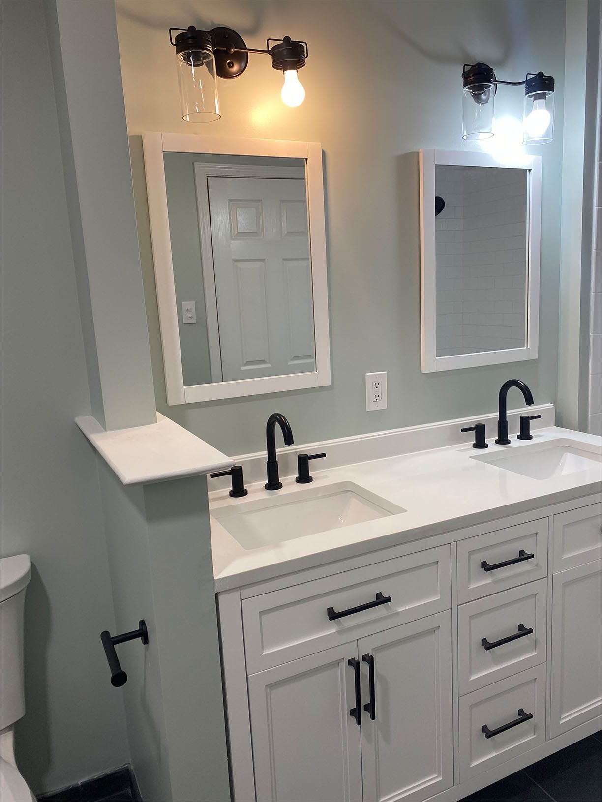 A bathroom with two sinks , two mirrors , and a toilet.