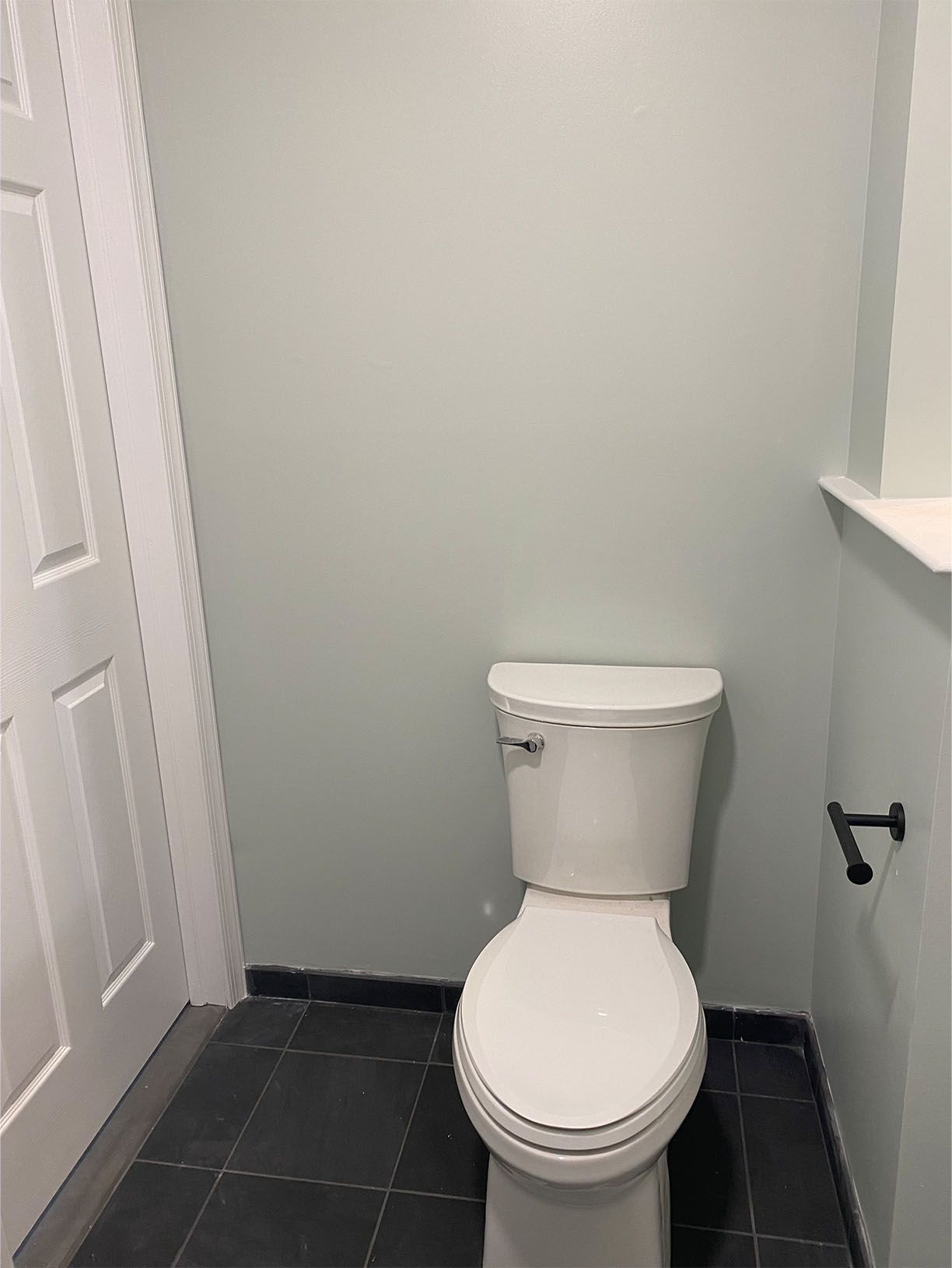 A toilet is sitting in a bathroom next to a door.