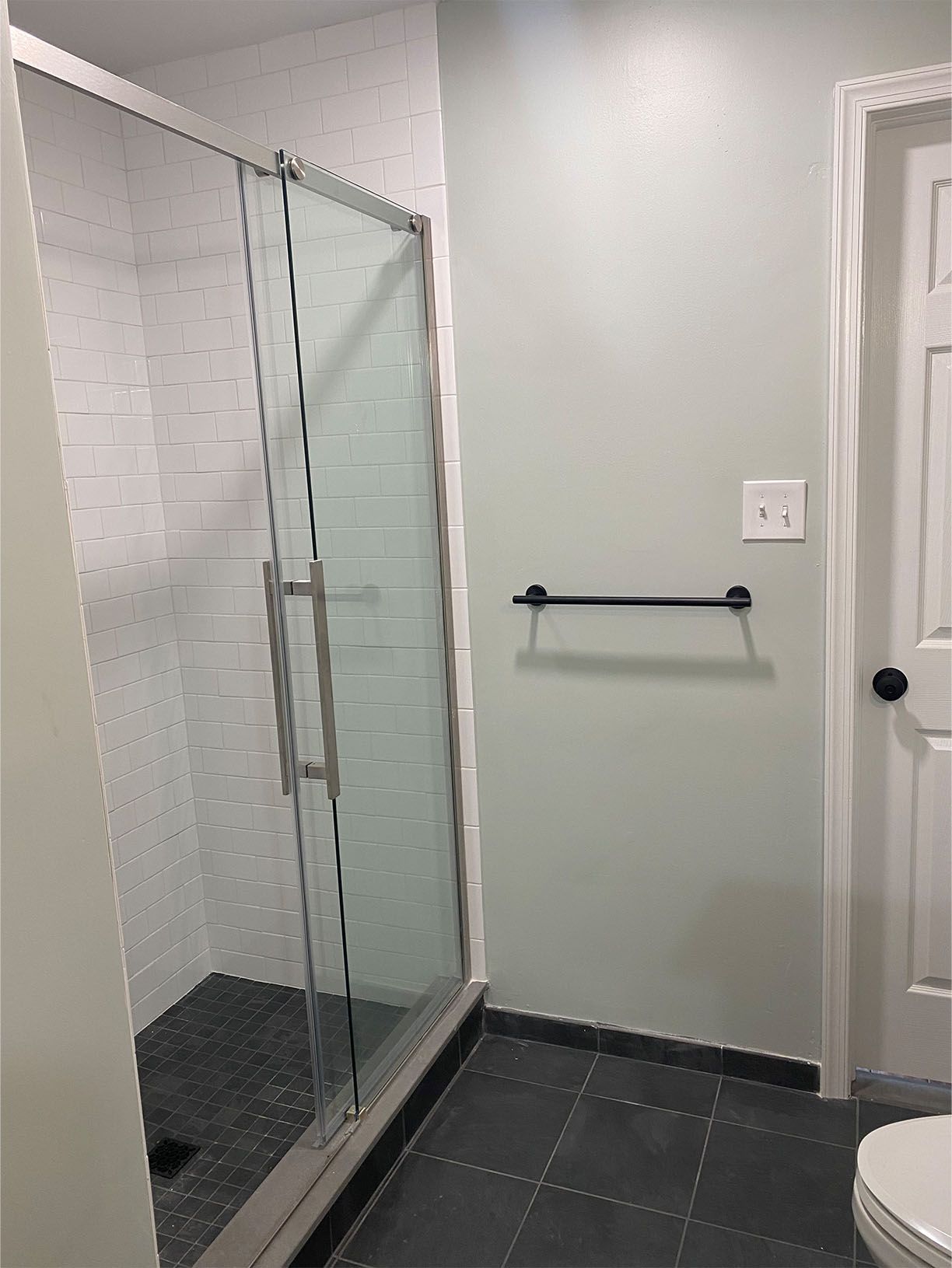 A bathroom with a toilet , shower , and towel rack.