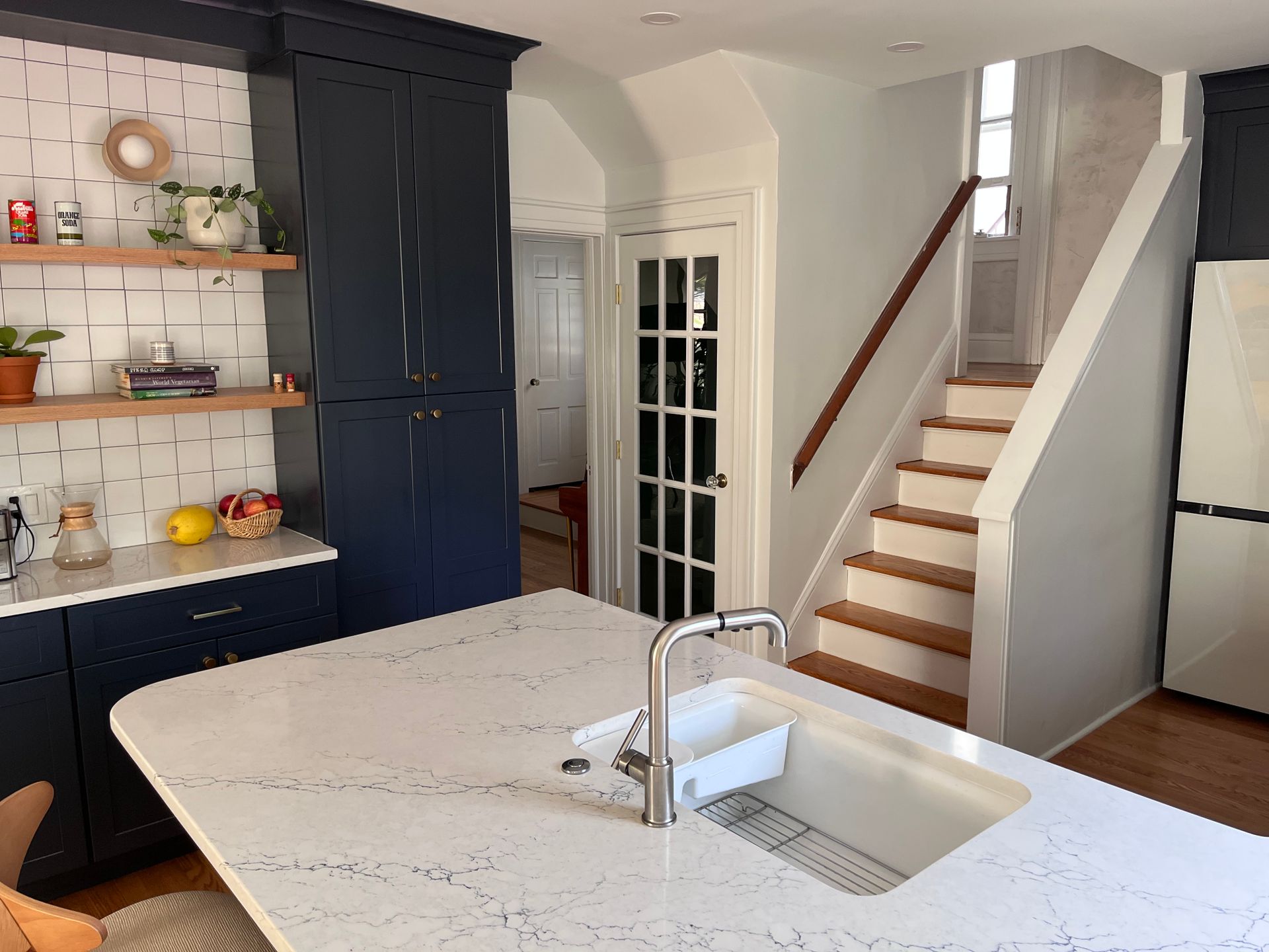 A kitchen with a sink and stairs leading up to the second floor