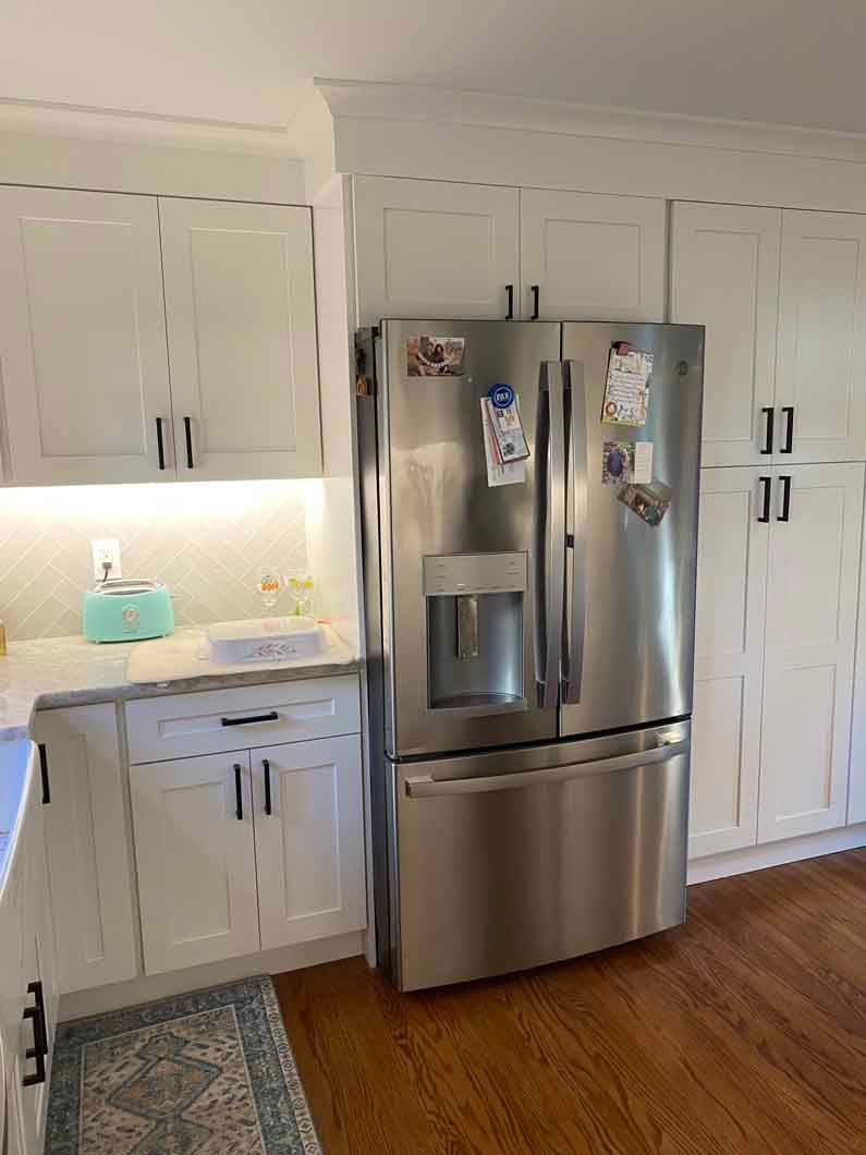 A kitchen with stainless steel appliances and white cabinets.