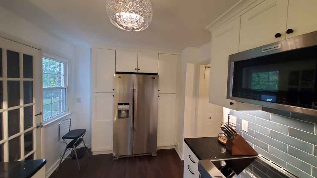 A kitchen with stainless steel appliances and white cabinets.