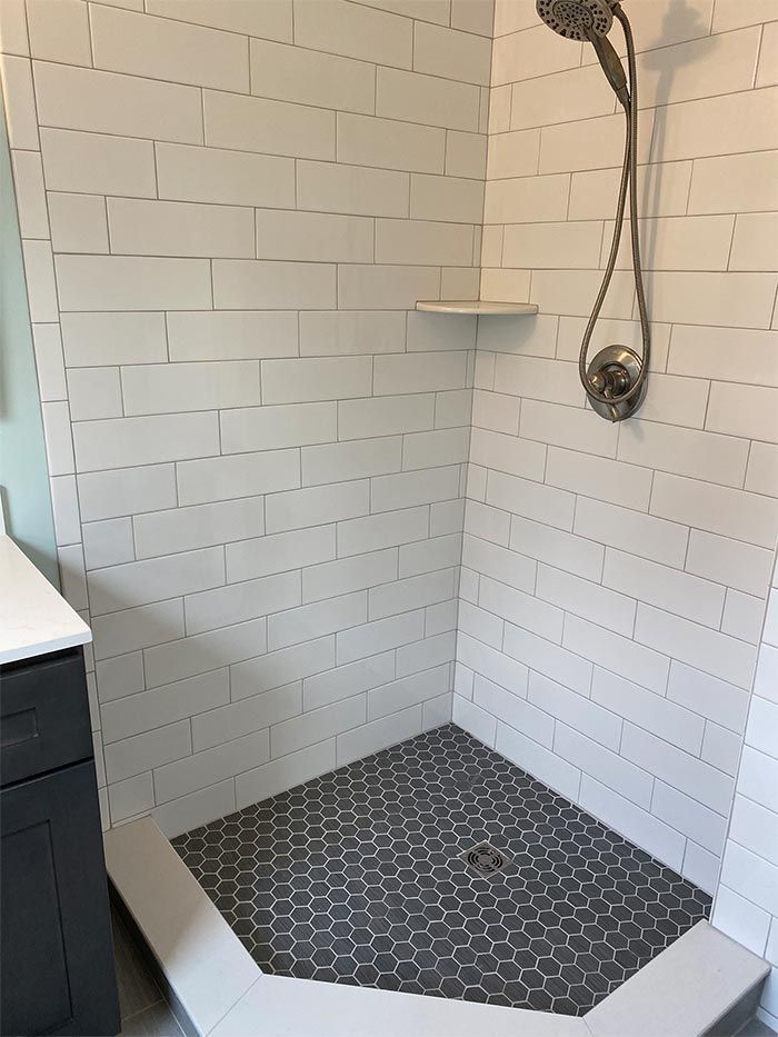 A shower stall with a shower head and a shelf in a bathroom.