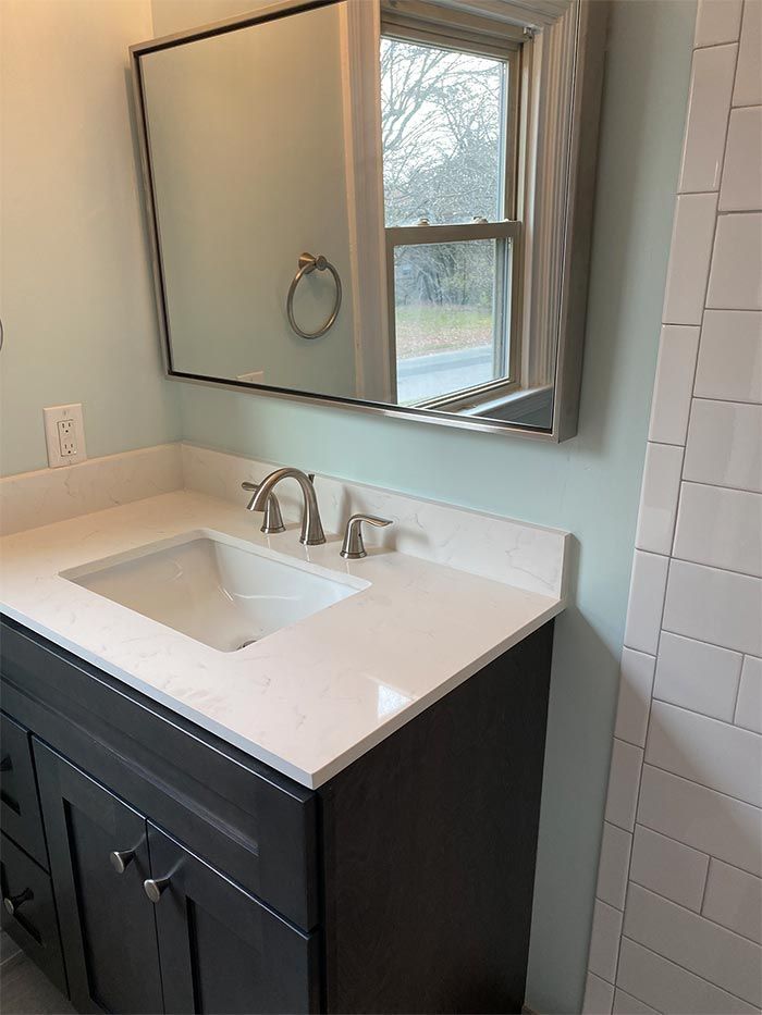 A bathroom sink with a mirror above it and a window.