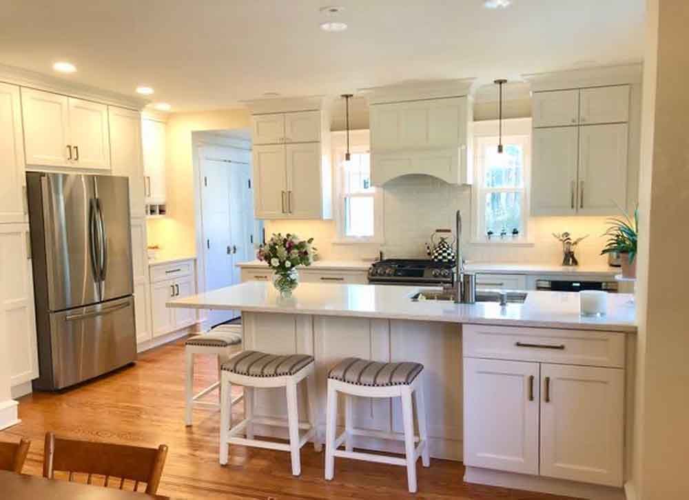 A kitchen with white cabinets , stainless steel appliances , and a large island.
